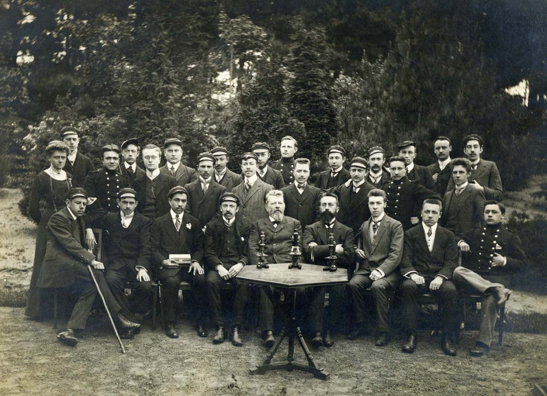 Julius Mac Leod (zittend in het midden) en Caesar de Bruycker (zittend, vierde van rechts), met studenten in de Plantentuin van de Gentse Universiteit, 1911. Foto Edgard Claessens. (Collectie Stad Antwerpen, Letterenhuis, tglhph50048)