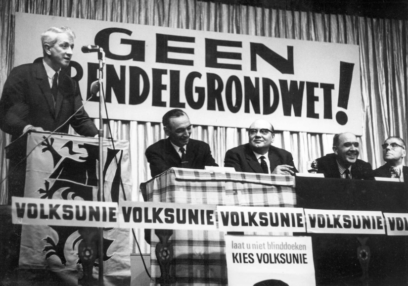 De VU verzette zich tegen de invoer van de zogenaamde Grendelgrondwet, waarbij de grondwet slechts kan worden gewijzigd bij een tweederdemeerderheid in het parlement en een meerderheid in elke taalgroep. Maurits Coppieters aan het woord tijdens een verkiezingsbijeenkomst van de VU op 6 mei 1965 in Oostende. (ADVN, VFA8643)
